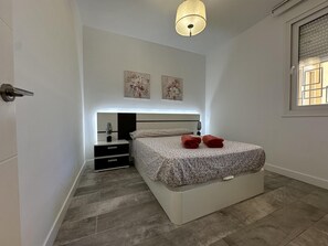 Een slaapkamer met een bed, nachtkastjes, een lamp en kunst aan de muur.