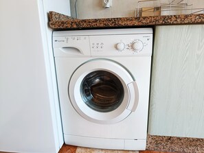 A front-loading washing machine with a control panel, set against a kitchen counter with a granite backsplash. - Renovated Apartment with Sea-View Terrace and Pool in Los Álamos, Torremolinos (Torremolinos)