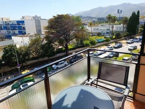 Een balkon met uitzicht op een parkeerplaats en gebouwen.