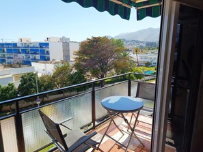 Ein Balkon mit Tisch und Stühlen, Blick auf eine Stadtlandschaft und ein Berg in der Ferne.