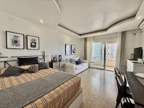 Een moderne hotelkamer met een bed, een bank, een eettafel en een balkon met uitzicht.