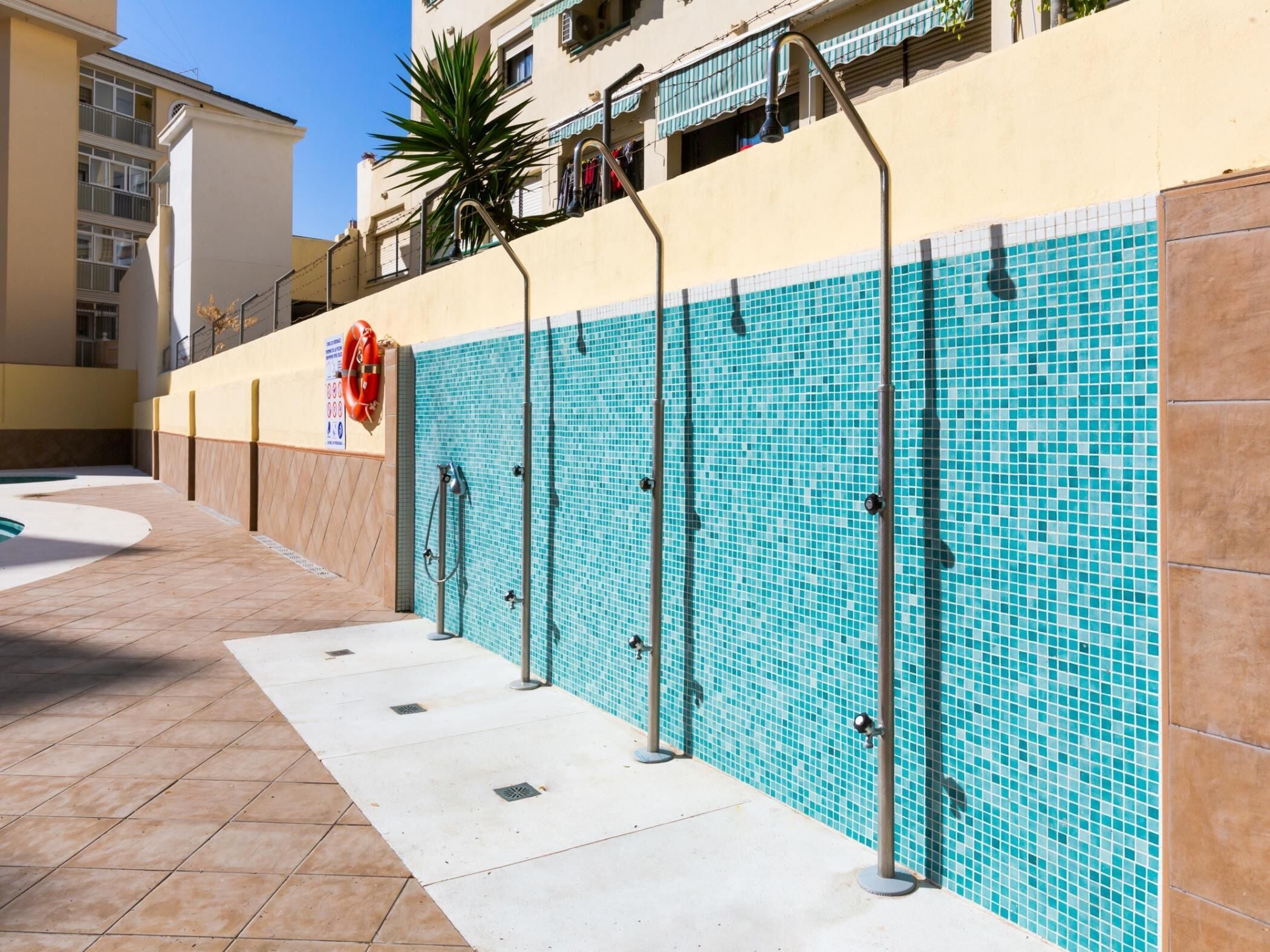 Zona de piscina con paredes y pasillo de baldosas, y un flotador salvavidas.