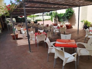 Een terras buiten met tafels en stoelen, waarvan sommigen het Coca-Cola logo hebben.