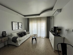Ein modernes Wohnzimmer mit einer Couch, einem kleinen Tisch, einem Sessel und einer Küchenzeile.