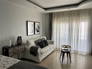 Ein modernes Wohnzimmer mit einer Couch, einem Beistelltisch, einer Lampe und einem Couchtisch.