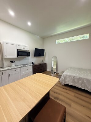 A compact room with a kitchenette, a bed, a mirror, and a window. - The R&R Studio  Cozy Private Guesthouse (Fayetteville)