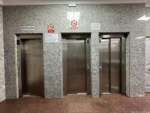 Three elevator doors in a lobby with granite walls, signs indicating 'MONTACARGAS' and 'PROHIBIDO FUMAR EN LOS ASCENSORES' (no smoking in the elevators). - One-Bedroom Apartment by Torremolinos Centre with WiFi and A/C (Torremolinos)