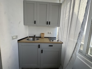 A compact kitchen with grey cabinets, a wooden countertop, a sink, and a stove. - One-Bedroom Apartment by Torremolinos Centre with WiFi and A/C (Torremolinos)