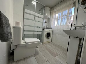 Uma casa de banho moderna com sanita, máquina de lavar e lavatório.