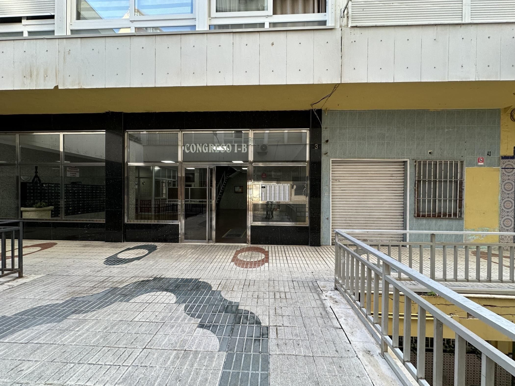 Ein Gebäude mit einer Schaufensterfront, auf der 'CONGRESO I-B' steht, und einem heruntergelassenen Rollo zur Rechten.