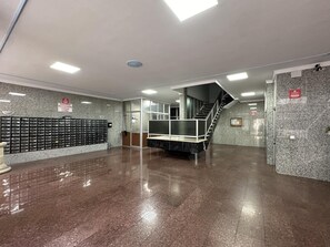 Um hall espaçoso com piso de mármore, escada e uma fileira de expositores de sapatos.