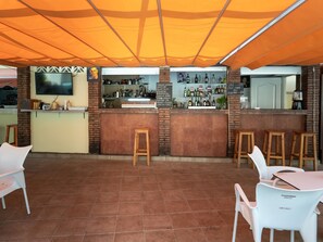 An outdoor cafe with a brick counter, bar stools, and a tiled floor. - Studio with Sea-View Terrace, Pool and WiFi in Central Torremolinos (Torremolinos)