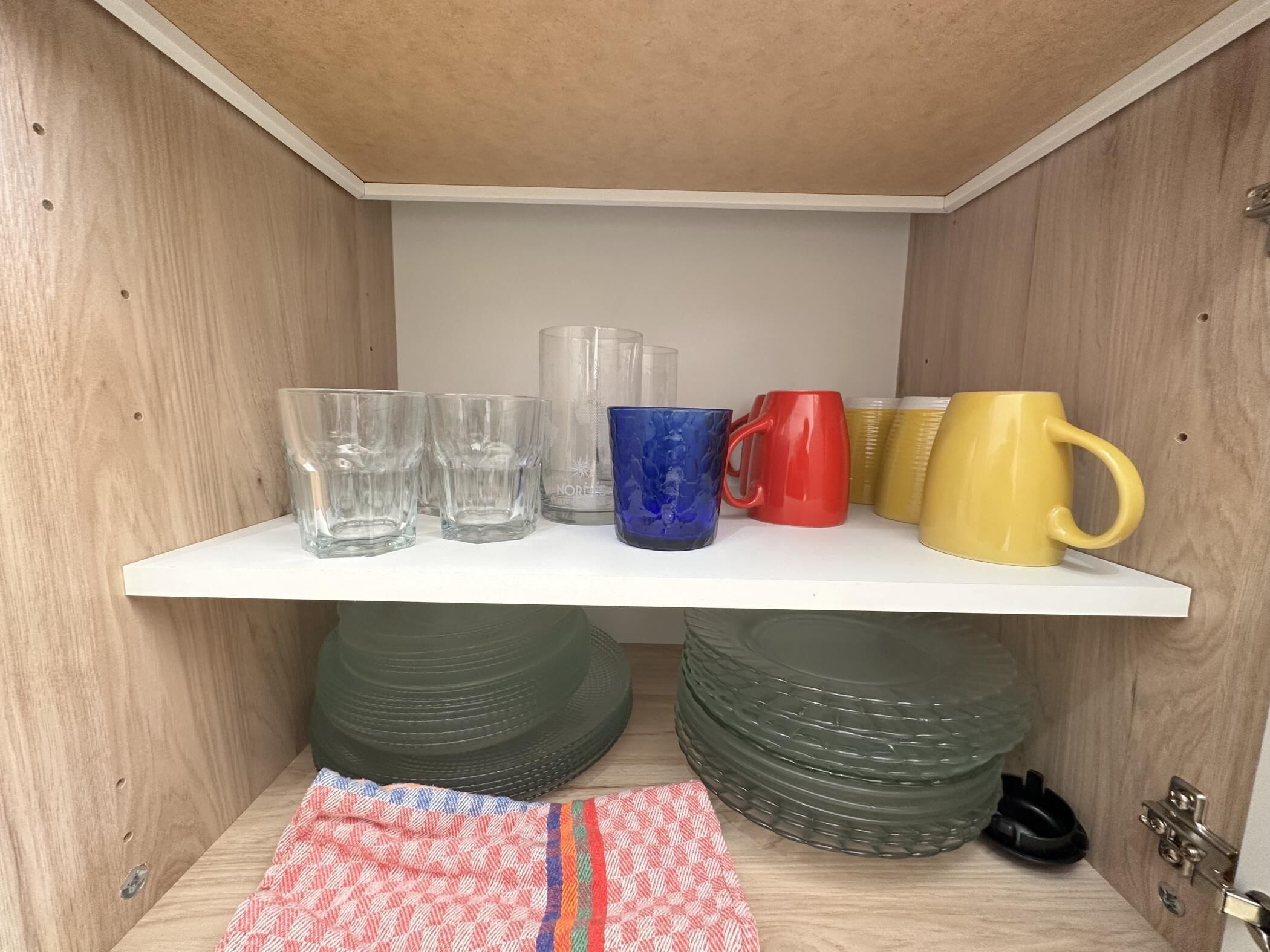 Um espaço de armazenamento com uma estante branca exibindo diversos recipientes de vidro e canecas.