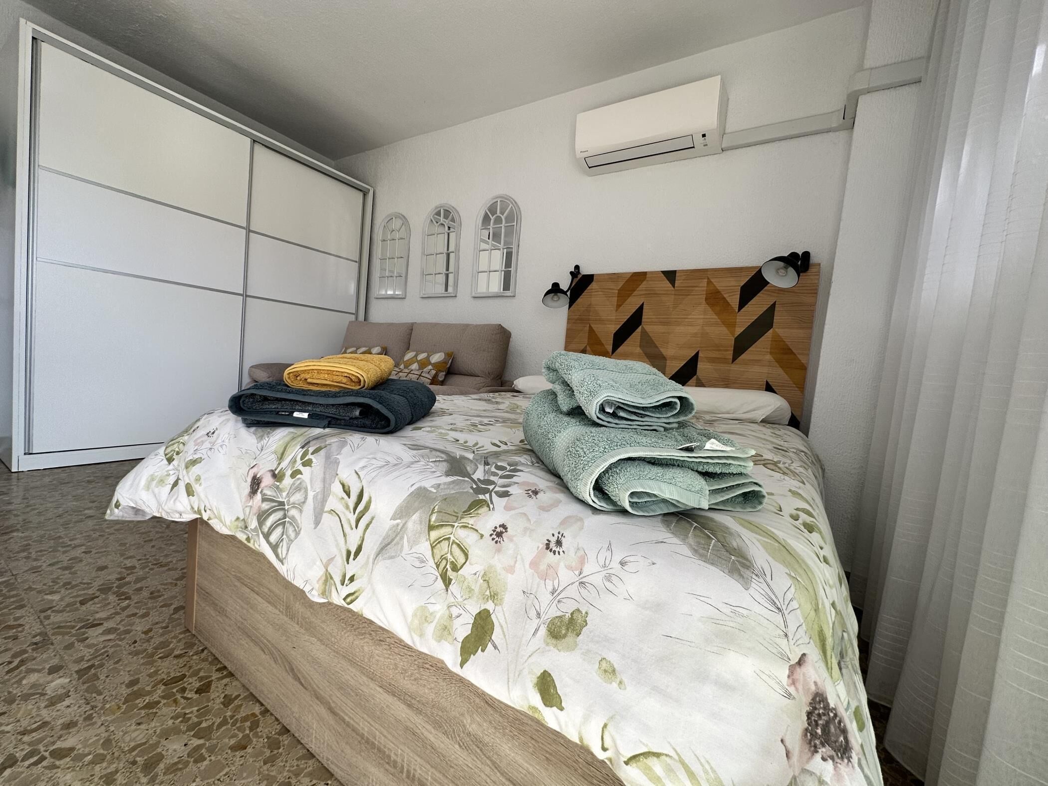 Un dormitorio con cama, armario y aire acondicionado.