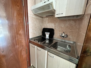 A compact kitchen with a stainless steel sink, a black stove, and wooden cabinets. - Studio with Sea-View Terrace, Pool and WiFi in Central Torremolinos (Torremolinos)