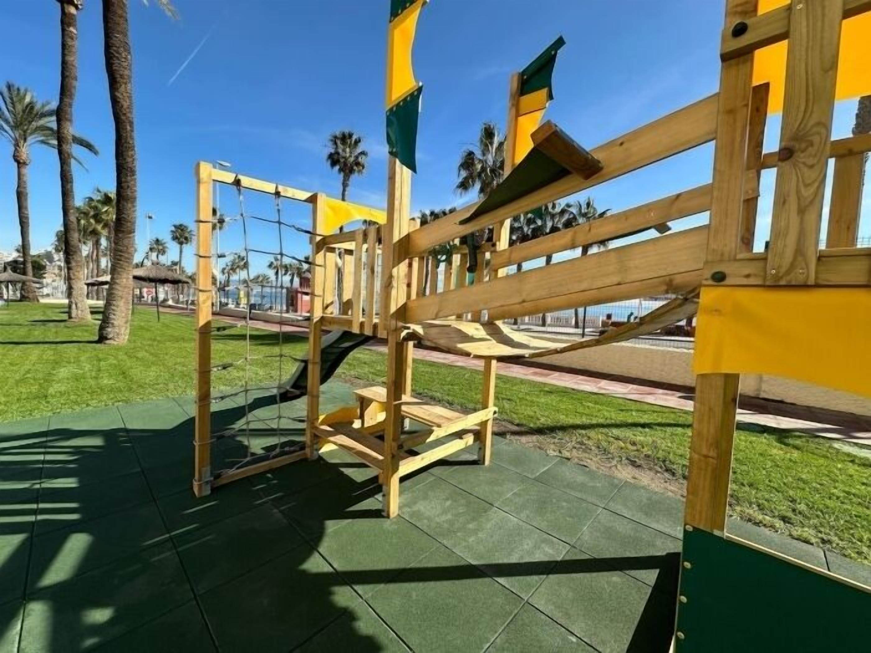 A playground with a wooden swing set and a slide.