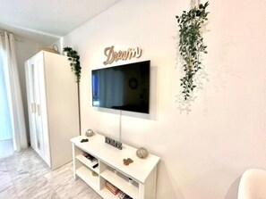 A modern living room with a mounted TV, a white console table, and a decorative wall piece. - Modern Apartment with Terrace and AC in the Centre, Steps from Train and Beach (Torremolinos)