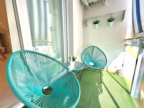A room with two turquoise chairs, a small table, and a potted plant. - Modern Apartment with Terrace and AC in the Centre, Steps from Train and Beach (Torremolinos)