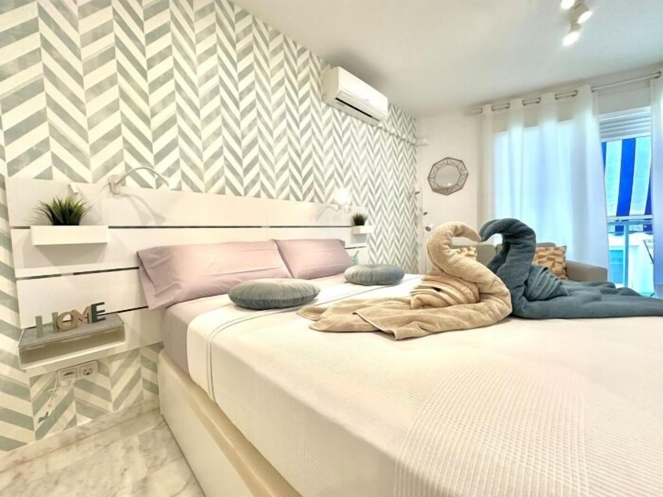Een moderne slaapkamer met een bed, een hoofdeinde, een wandairconditioner en een raam met gordijnen.