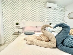 Ein Schlafzimmer mit Bett, Kissen, einem Nachttisch, einer Wand-Klimaanlage und einem Wandpapier mit Muster.