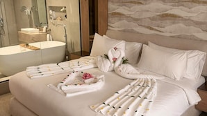 Ein Hotelzimmer mit einem großen Bett, einem Badezimmer mit einer Badewanne und einem Spiegel.