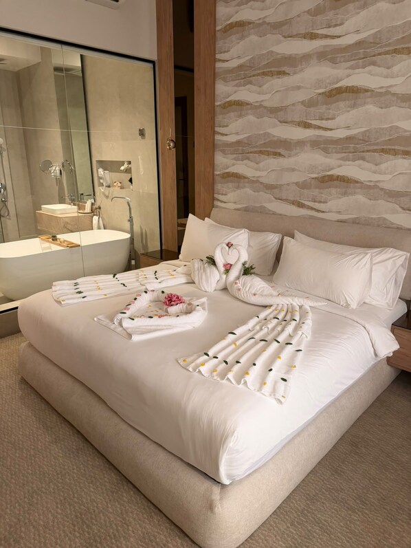 Habitación de hotel con una cama grande, un baño con bañera y un espejo.