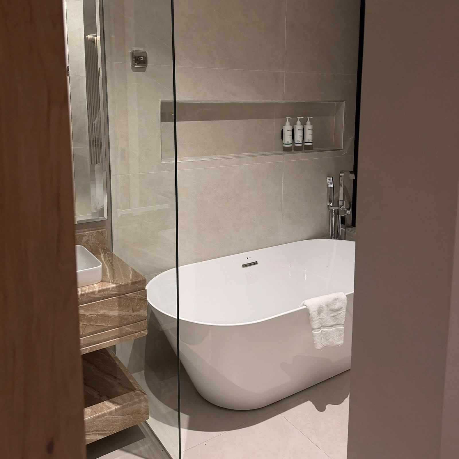 Un baño moderno con una bañera independiente, cabina de ducha de vidrio y encimera de mármol.