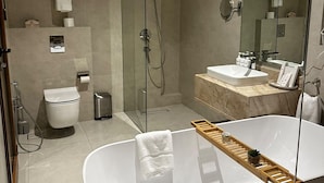 Ein modernes Badezimmer mit einer freistehenden Badewanne, einer Duschkabine und einem Waschtisch mit Spiegel.