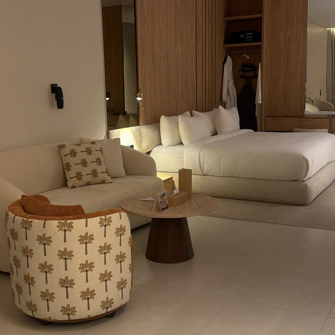 A modern living room with a sofa, a round coffee table, and a bed.
