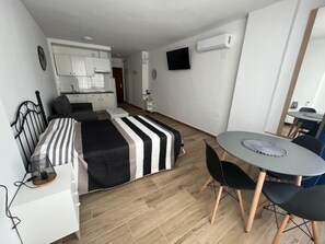 A compact room with a bed, a small desk, a chair, a table, and a kitchenette area. - Sea-View Studio with Pool, 100 m from the Centre of Torremolinos (Torremolinos)