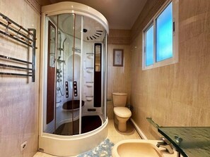 Een badkamer met een douchecabine van glas, een toilet en een wastafel.