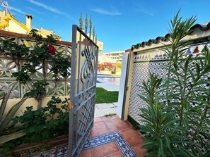 A gated entrance with a decorative metal gate, a tiled pathway, and a potted plant. - 3-Bedroom Villa with Garden, BBQ and Pool, 350 m from the Beach (Torremolinos)
