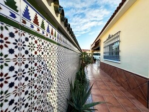A corridor with patterned tile walls, a tiled floor, and a window on the right.