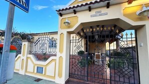 Uma entrada fechada por portão de metal, com uma placa em cima.