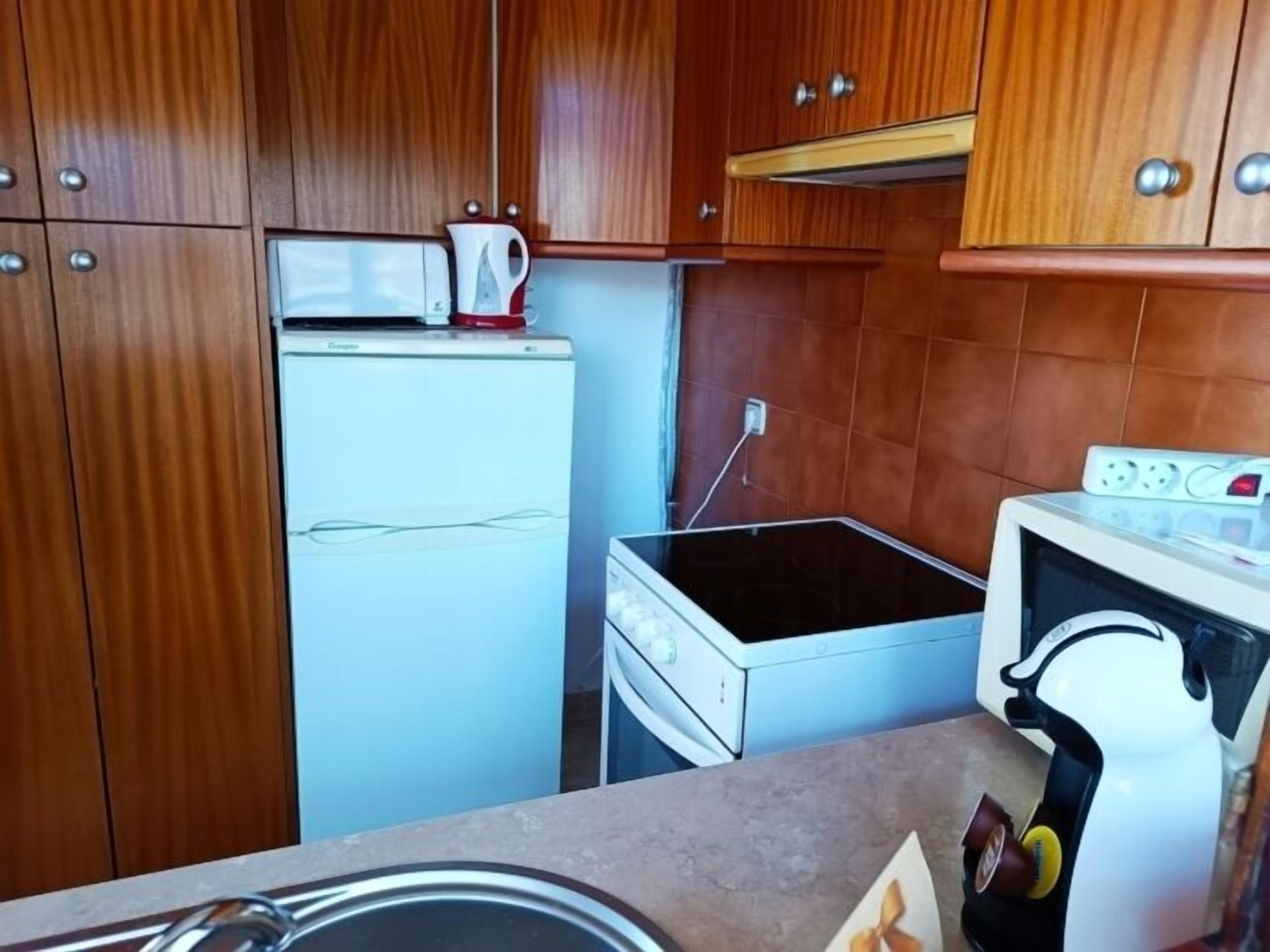 Cocina compacta equipada con refrigerador, microondas, estufa y pileta.