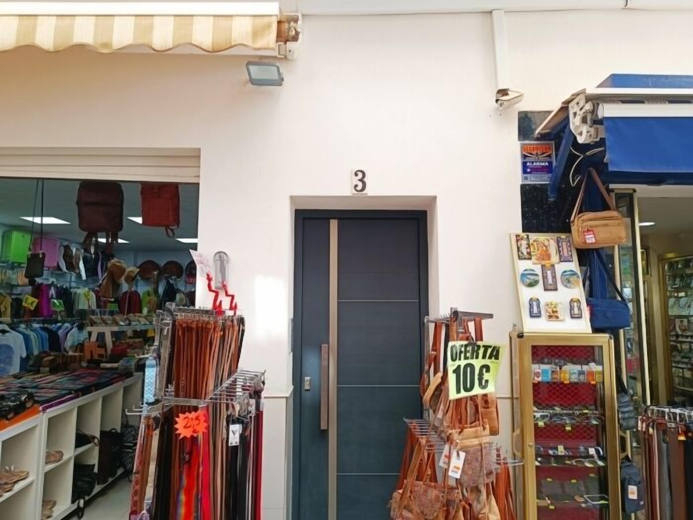 Een etalage met een gesloten deur, verschillende artikelen te zien zoals tassen en accessoires, en een prijsbordje met 10 cent.