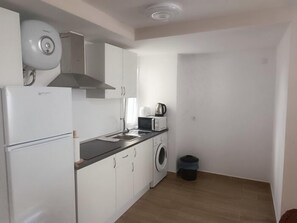 Eine kleine Küche mit Kühlschrank, Mikrowelle und Waschmaschine.