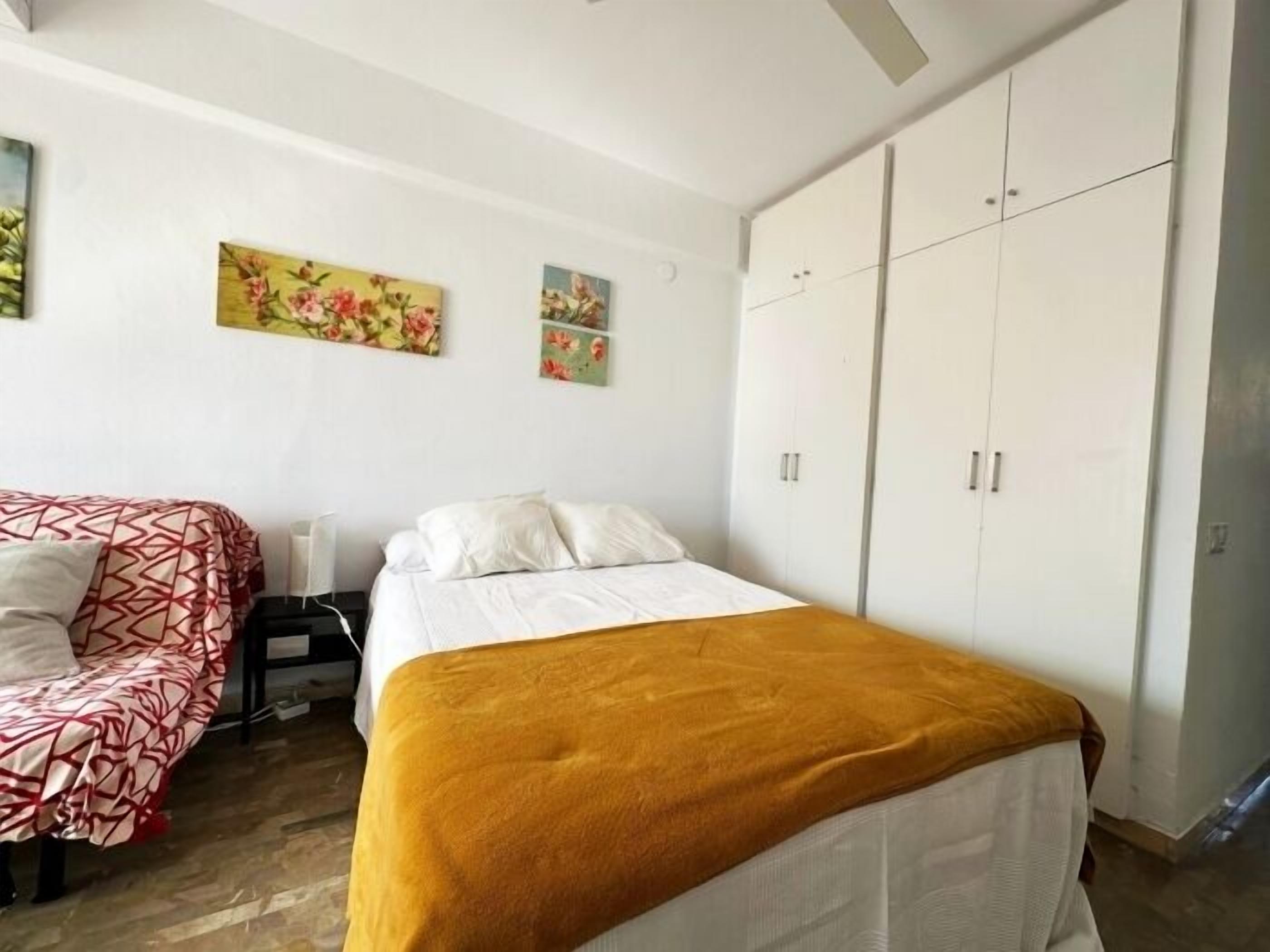 A bedroom with two beds, a wardrobe, and artwork on the wall.