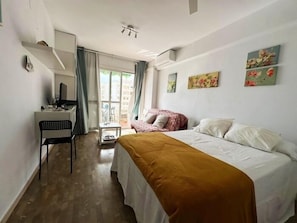 Een slaapkamer met een bed, een bureau, een stoel en een raam met gordijnen.