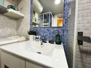 Een badkamer met een witte wastafel, een spiegel en een wand betegeld met blauwe tegels.
