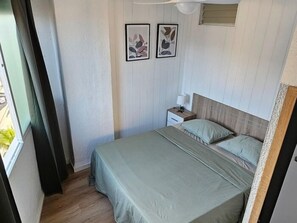 Een slaapkamer met een bed, nachtkastje en raam.