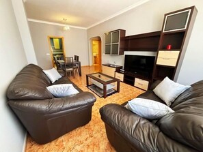 A living room with two sofas, a coffee table, and a TV stand. - 2-Bedroom Apartment 100 m from Bajondillo Beach and the Town Centre (Torremolinos)