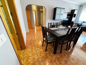 A dining area with a table and chairs, a kitchen area with cabinets, and a hallway leading to another room. - 2-Bedroom Apartment 100 m from Bajondillo Beach and the Town Centre (Torremolinos)