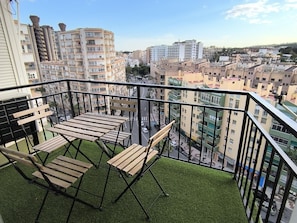 Een balkon met uitzicht op een stadsbeeld, met meerdere gebouwen en een heldere lucht.