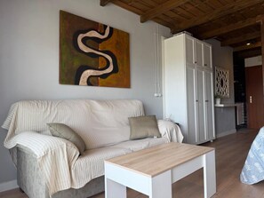 A living room with a sofa, a coffee table, and a painting on the wall. - 10th-Floor Studio with Terrace and Views in Central Torremolinos (Torremolinos)