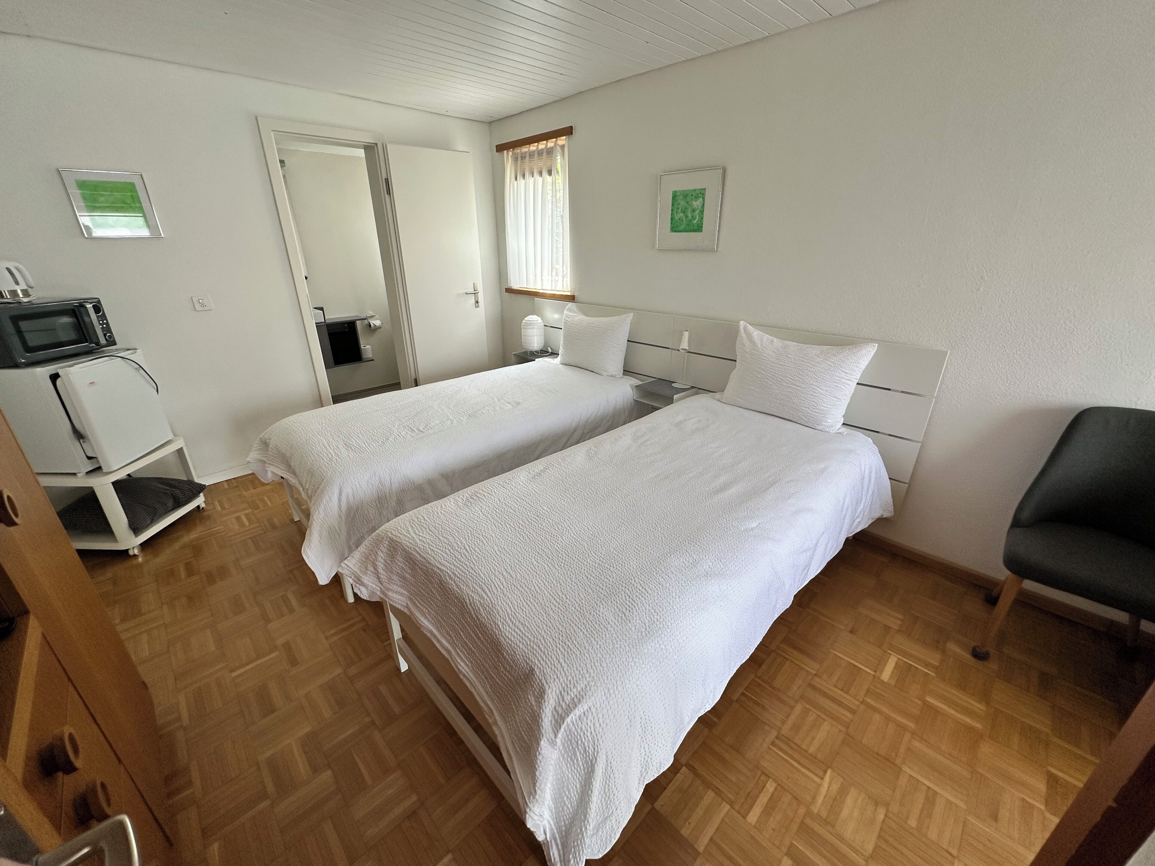 Habitación de hotel con dos camas, microondas, refrigerador y una silla.