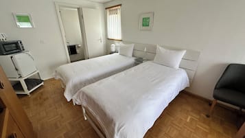 Habitación de hotel con dos camas, microondas, refrigerador y una silla.