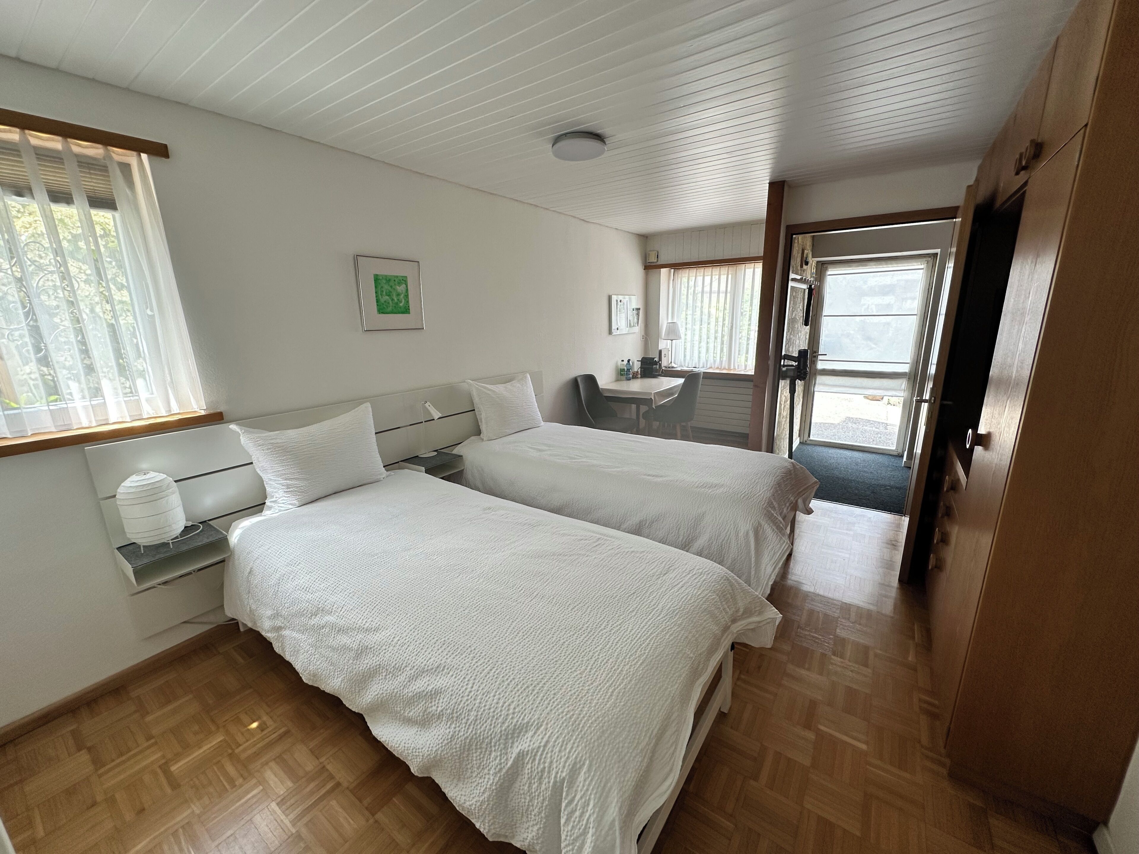 Ein Hotelzimmer mit zwei Betten, einem Schreibtisch und Blick ins Freie.