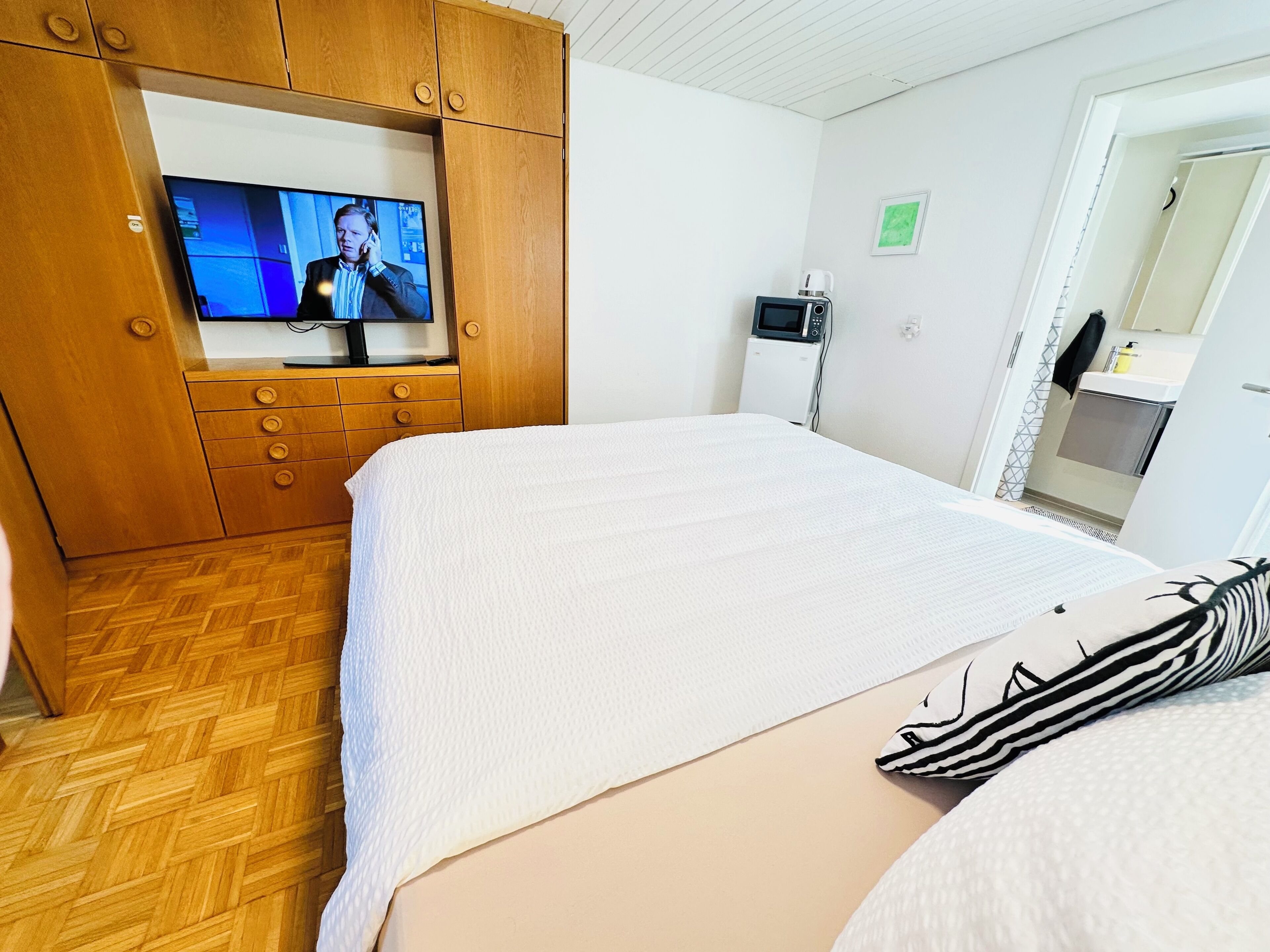 Ein Hotelzimmer mit einem Bett, einem Fernseher, einer Mikrowelle und einer kleinen Küchenzeile.
