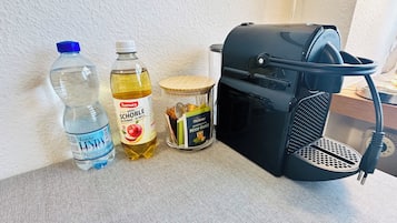 Un plan de travail de cuisine avec une bouteille d’eau, une bouteille d’huile d’olive, un pot de miel et une machine à café.